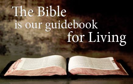 An open Bible is displayed on a surface with the phrase "The Bible is our guidebook for Living" superimposed on a softly lit, warm background.